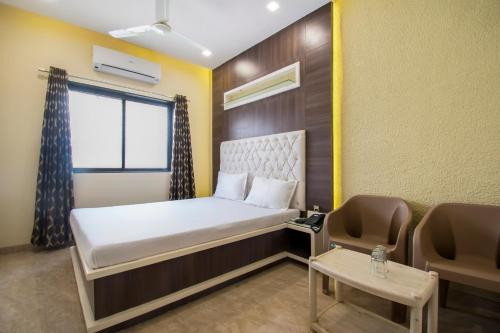 a small room with a bed and a chair at Aasra Lodge in Ratnagiri