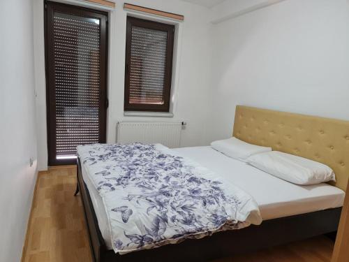 ein Schlafzimmer mit einem Bett mit einer blauen und weißen Decke in der Unterkunft APARTMANI SK in Brčko