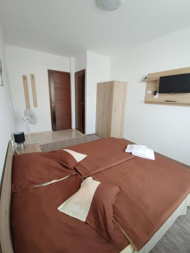 ein großes braunes Bett in einem Zimmer mit einem TV in der Unterkunft Fiesta Apartman in Miskolctapolca
