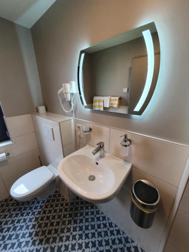 a bathroom with a sink and a toilet and a mirror at Wirtshaus & Hotel Zur Alten Brauerei Zapf in Uettingen