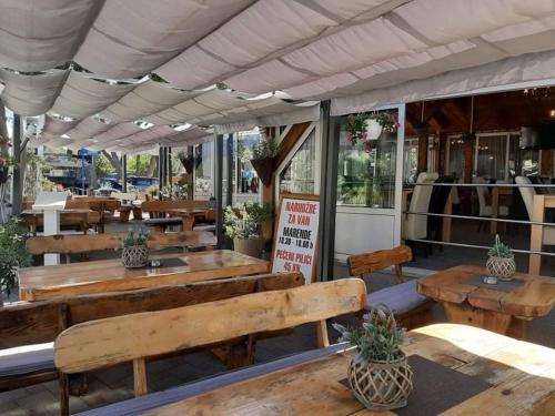 a restaurant with wooden benches and tables in front at Apartmani Bonić in Vodice