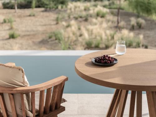 a wooden table with a glass of milk and a plate of fruit at Seven Rocks in Paliouri
