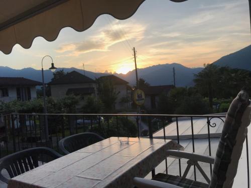a table and chairs on a balcony with the sunset at Al Centrale di Piazzogna in Gambarogno