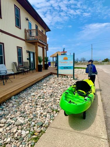 a man standing next to a green kayak on the side of a house at Paradise Inn On the Beach in Port Elgin