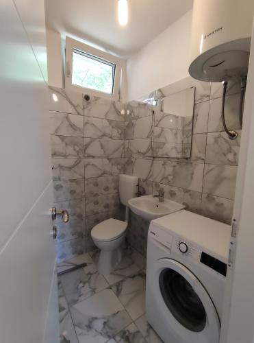 a bathroom with a toilet sink and a washing machine at Apartment Bajama in Omiš