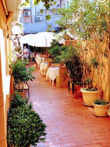 a patio with tables and chairs and potted plants at Hotel Tahiti in Viareggio