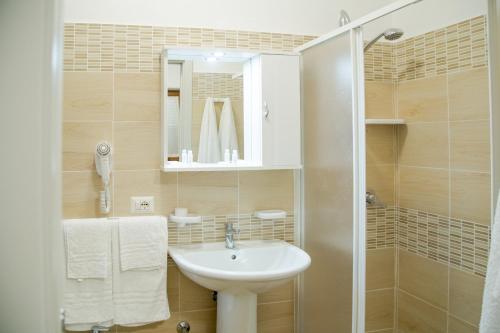 La salle de bains est pourvue d'un lavabo blanc et d'une douche. dans l'établissement La Conchiglia, à San Nicola Arcella