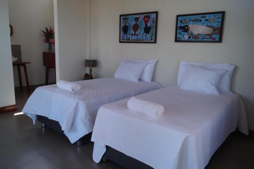 two beds in a room with white sheets and pillows at Indano Art Lodge in Lamas
