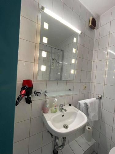 a white bathroom with a sink and a mirror at Pension am Meer in Norddeich