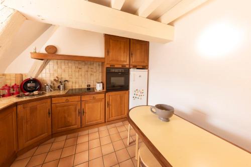 a kitchen with wooden cabinets and a white refrigerator at La Lirosane, 3 studios, 3,7km du Zoo, Centre-ville in Saint-Aignan