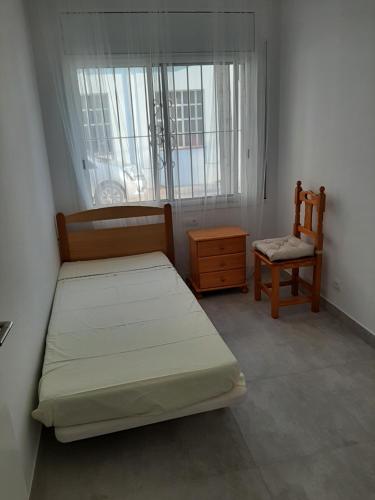 a bedroom with a bed and a chair and a window at Casa Les Buganvilles in Deltebre