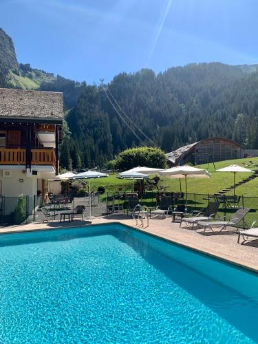 a swimming pool with chairs and tables and umbrellas at Hameau des Prodains - Hôtel in Morzine