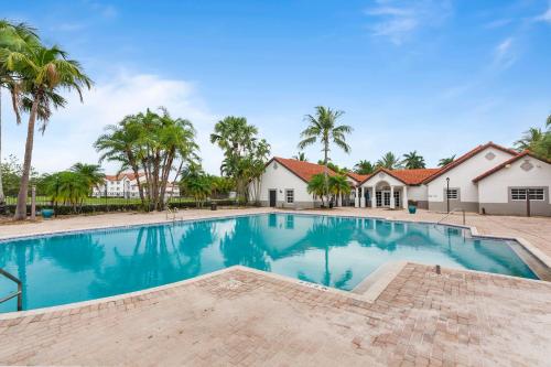 a swimming pool in front of a house with palm trees at Kasa Delray Beach South Florida in Delray Beach