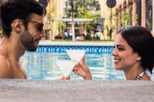 a man and a woman holding drinks in a swimming pool at Hotel Boutique Sol y Luna SPA in Ajijic