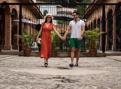a man and woman walking down a street holding hands at Hotel Boutique Sol y Luna SPA in Ajijic