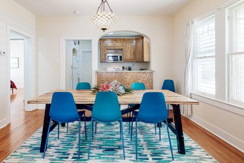 a dining room with a wooden table and blue chairs at Sea Glass Cottage in Galveston