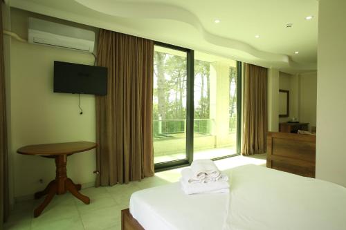 - une chambre avec un lit, une table et une télévision dans l'établissement Magnetiti Hotel, à Ureki
