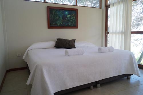 a bedroom with a white bed with two pillows on it at Indano Art Lodge in Lamas