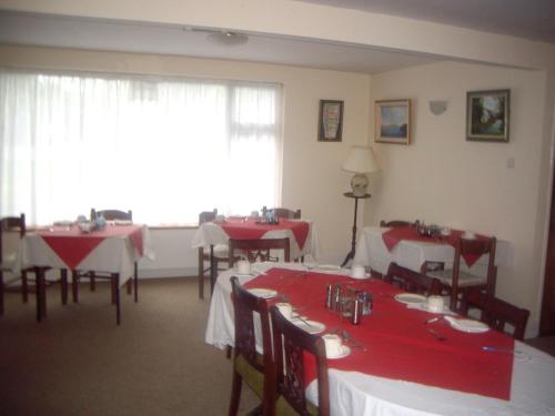 a dining room with red tables and chairs and a window at Fountain House B&B in Macroom