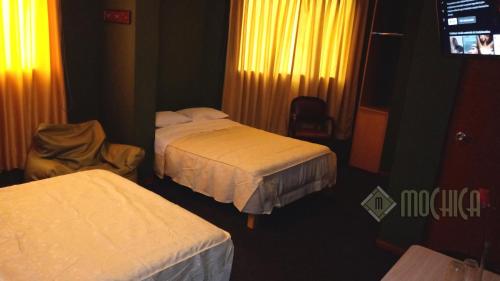 a hotel room with two beds and a television at Hostal Residencial Mochica in Lima