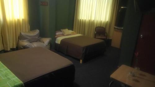 a hotel room with two beds and a chair at Hostal Residencial Mochica in Lima