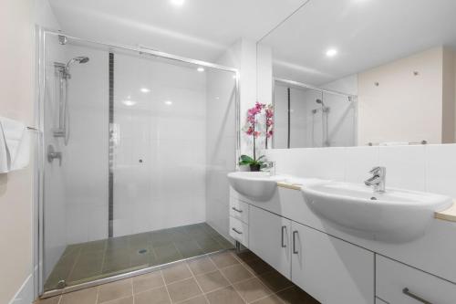 a white bathroom with two sinks and a shower at Drift Apartments - Tweed Coast Holidays ® in Kingscliff
