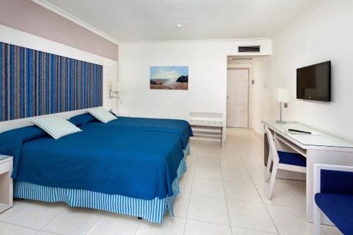 a bedroom with a blue bed and a desk at Tigotan Lovers & Friends Playa de las Americas - Adults Only (+18) in Playa de las Americas