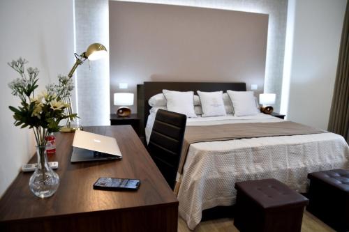 a bedroom with a bed and a desk with a laptop at Pompei Luxury Suite in Pompei