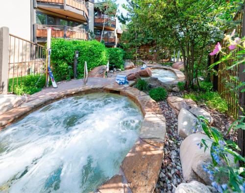 a hot tub in a backyard with rocks and trees at Laurelwood Condominiums 113 in Snowmass Village