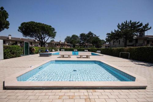 a swimming pool with blue water in a courtyard at Holiday home Porto Santa Margherita 40286 in Porto Santa Margherita di Caorle