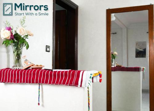 a vase of flowers on a table with a mirror at Ayouz House Hotel in Dakhla