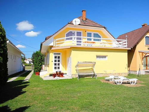 a yellow house with a lawn in front of it at Holiday home in Balatonlelle 40449 in Balatonlelle