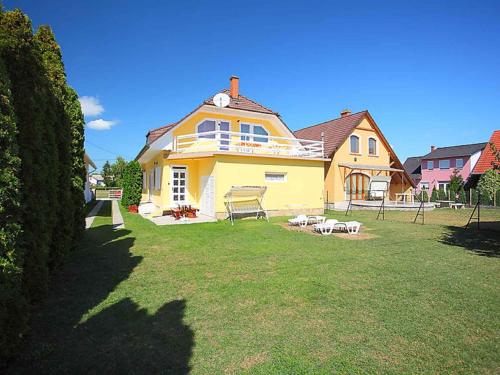a large yellow house with a playground in the yard at Holiday home in Balatonlelle 40449 in Balatonlelle