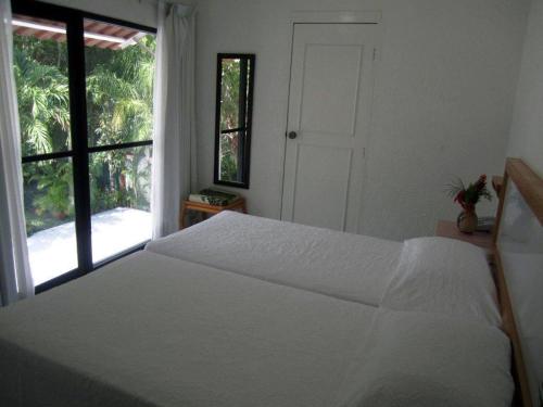 a bedroom with a white bed and a window at Hotel Olinalá Diamante in Acapulco