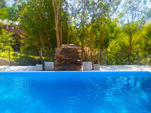 a blue swimming pool with a stack of bricks and trees at Departamento Cerro Negro in Villa General Belgrano