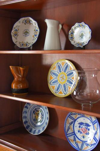 a shelf with plates and vases on it at Apartamentos Tres Llaves Palacio de Vela de los Cobos in Úbeda