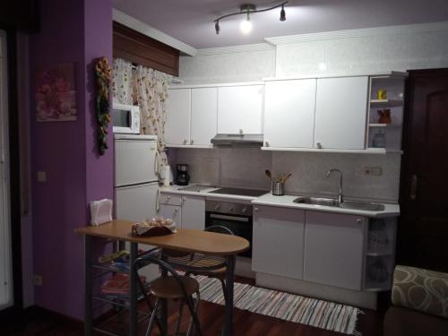 uma cozinha com armários brancos, uma mesa e um lavatório em Apartamento Duplex Vigo em Vigo