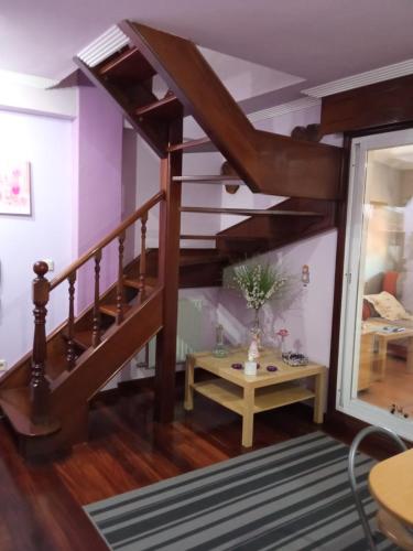 Apartamento Duplex Vigo في فيغو: غرفة معيشة مع درج خشبي وطاولة