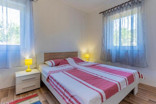 a bedroom with a large bed and two windows at Apartmani Cres in Cres