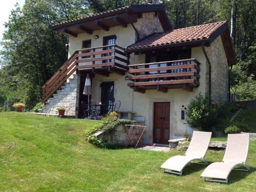 a house with two white chairs in front of it at Holiday home in Madonna Del Sasso 22866 in Madonna del Sasso