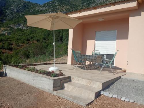 a patio with an umbrella and a table and chairs at Adriatic Sunset House in Petrovac na Moru