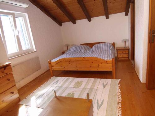 ein Schlafzimmer mit einem Holzbett und einem Fenster in der Unterkunft Holiday home in Veli Losinj 36387 in Veli Lošinj