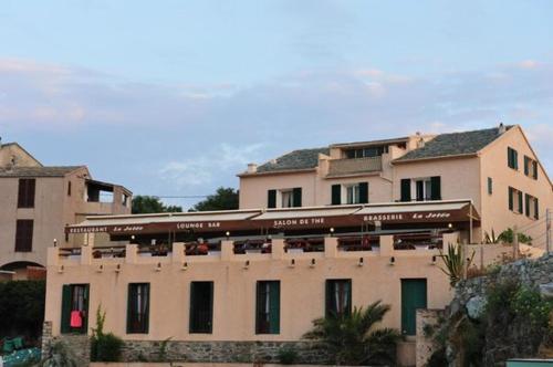 a large tan building with a lot of windows at Hôtel de la jetée in Centuri