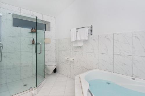 a bathroom with a tub and a shower and a toilet at The Tauranga on the Waterfront in Tauranga