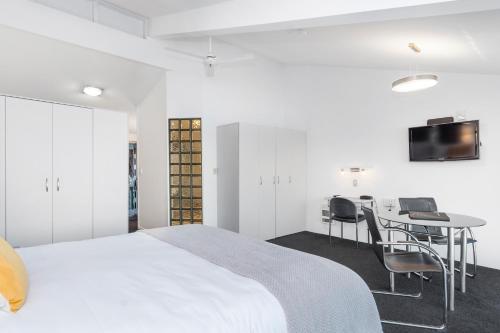 a bedroom with a bed and a desk and a tv at The Tauranga on the Waterfront in Tauranga