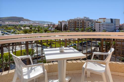 a white table and chairs on a balcony with a city at Tigotan Lovers & Friends Playa de las Americas - Adults Only (+18) in Playa de las Americas