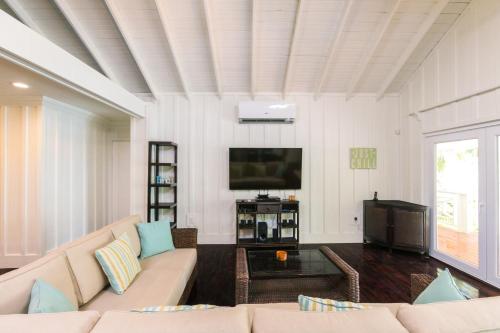 a living room with a couch and a flat screen tv at Serenity Beach Home in West End