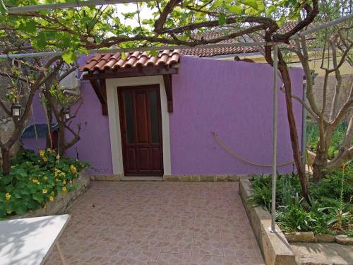 a purple house with a door and a walkway at Apartment in Veli Losinj 14933 in Veli Lošinj
