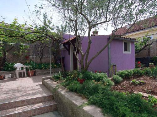a purple house with a tree in a yard at Apartment in Veli Losinj 14933 in Veli Lošinj