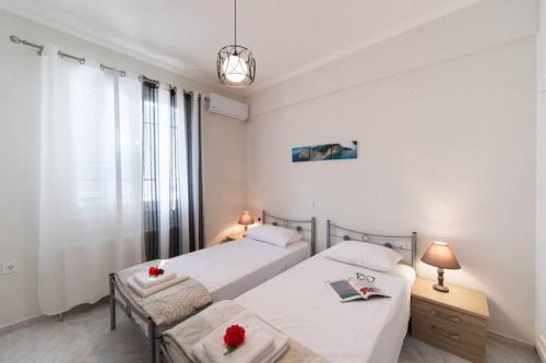 2 camas en un dormitorio con paredes blancas y ventana en Apartment in the Center of Lefkas, en Lefkada